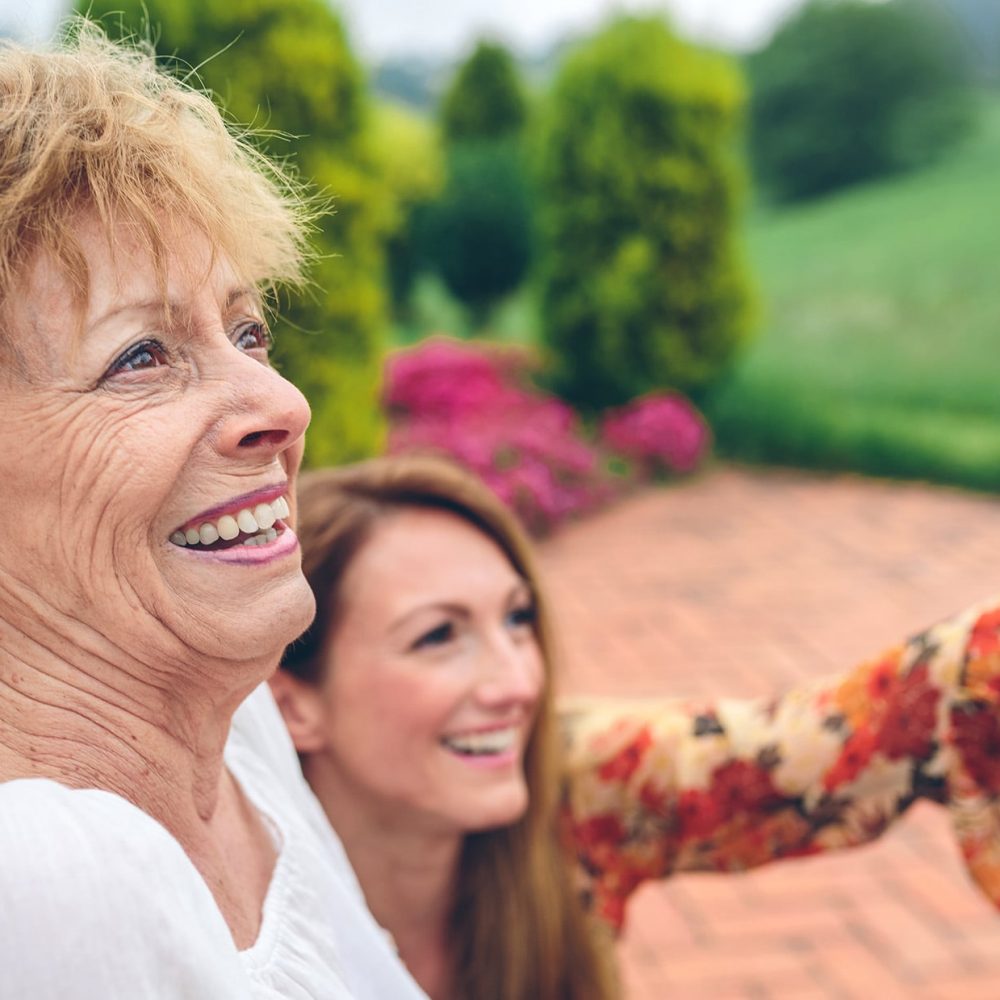 Senior woman in a wheelchair with her daughter looking at the landscape
